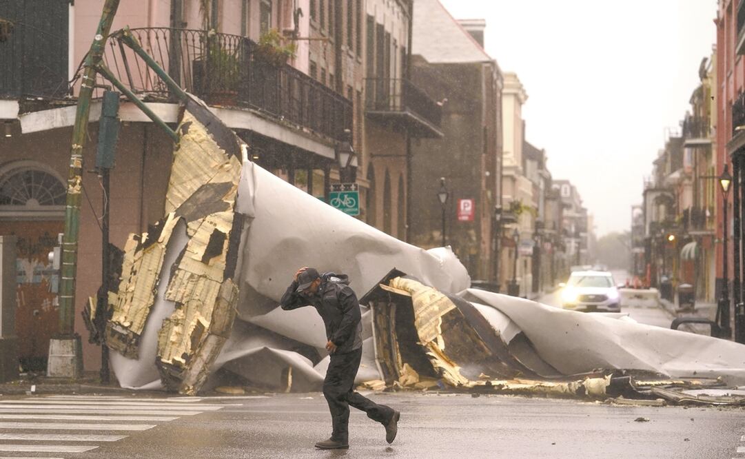 Un hombre pasa junto a un pedazo de techo que Ida despegó de un edificio en Nueva Orleans. Foto: Erik Gay/ EL UNIVERSAL.