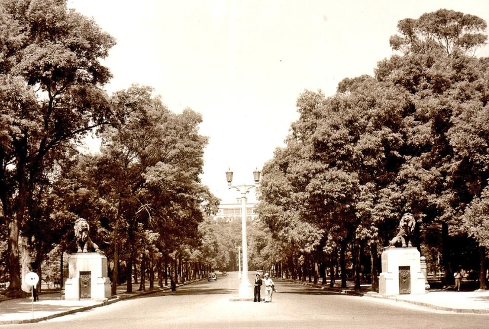 Dos hombres son retratados en la entrada al Bosque de Chapultepec en una tarjeta postal de los años veinte. En ambos lados de la toma se aprecian los leones de bronce del escultor Georges Gardet que se conservan en este sitio hasta la actualidad. Al fondo destaca el Castillo de Chapultepec. Imagen: Col. Villasana-Torres