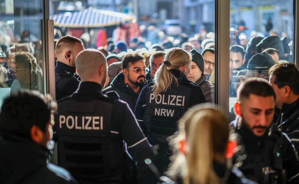 Policías y clientes bancarios preocupados se encuentran frente a una sucursal del banco Sparkasse en Gelsenkirchen, oeste de Alemania, el 30 de diciembre de 2025, tras un robo. Foto: AFP
