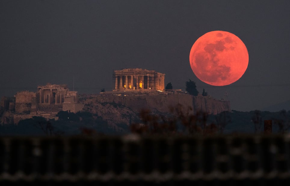 Cercana, grande y "de sangre": un eclipse lunar total particularmente raro por su tamaño ofreció anoche un espectáculo celestial visto por miles de personas de punta a punta del planeta. La superluna se eleva detrás del Partenón en la Acrópolis de Atenas, Grecia (Foto: AP)