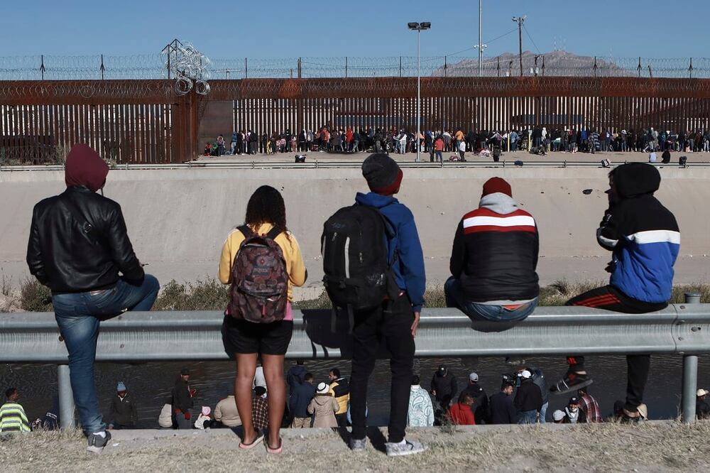 Migrantes observan a otros junto al muro fronterizo en Ciudad Juárez, México, el 21 de diciembre de 2022. Foto: AP
