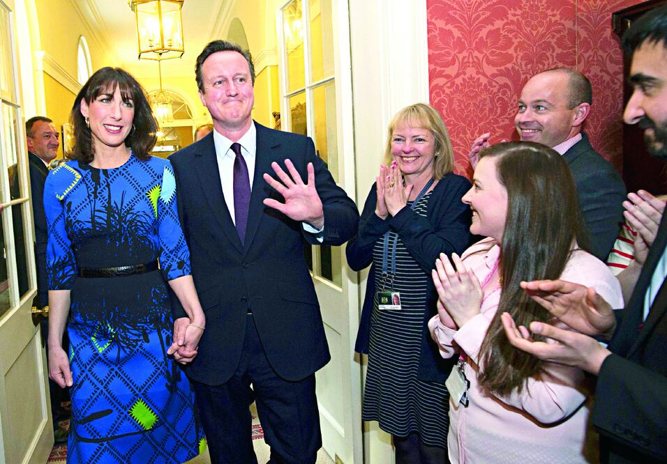 Empleados aplauden a la llegada del primer ministro británico David Cameron y su esposa Samantha al número 10 de Downing Street, en Londres, tras la victoria de Cameron en las elecciones del jueves (STEFAN ROUSSEAU / REUTERS)