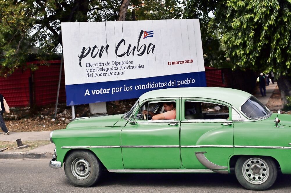 Un auto clásico circulaba ayer frente a un cartel alusivo a las elecciones generales en La Habana, Cuba. (ALEJANDRO ERNESTO. EFE)