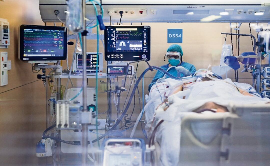 A healthcare worker wearing a protective suit attends to a COVID-19 coronavirus patient - Photo: Pau Barrena/AFP