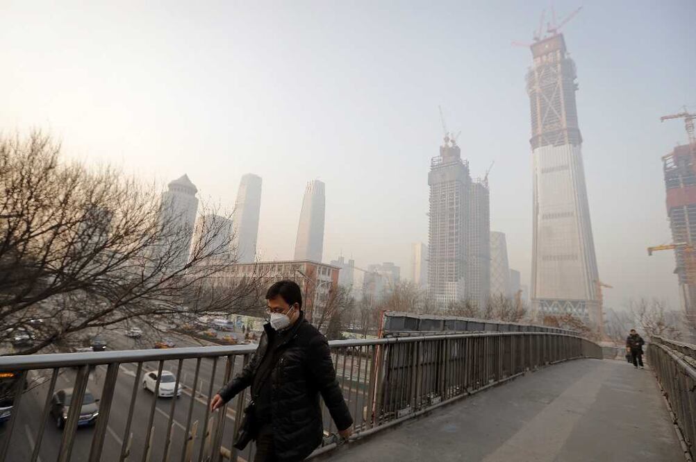 Un hombre que tiene una mascarilla para protegerse de la contaminación del aire camina por un puente peatonal en Beijing, antes de la pandemia. Foto: AP/Andy Wong, archivo