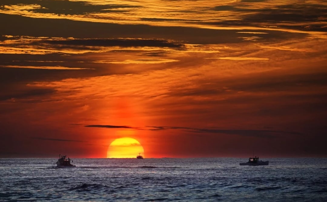 El sol se levanta en el horizonte del mar donde alcanzan a divisarse embarcaciones pesqueras en el océano Atlántico, frente a las costas de Kennebunkport, Maine, el 8 de septiembre de 2022. Foto: AP