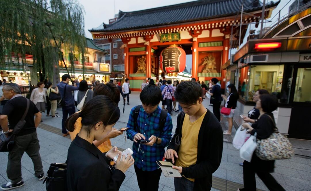 Varios universitarios japoneses prueban en su móvil el juego "Pokémon Go"  (EFE)
