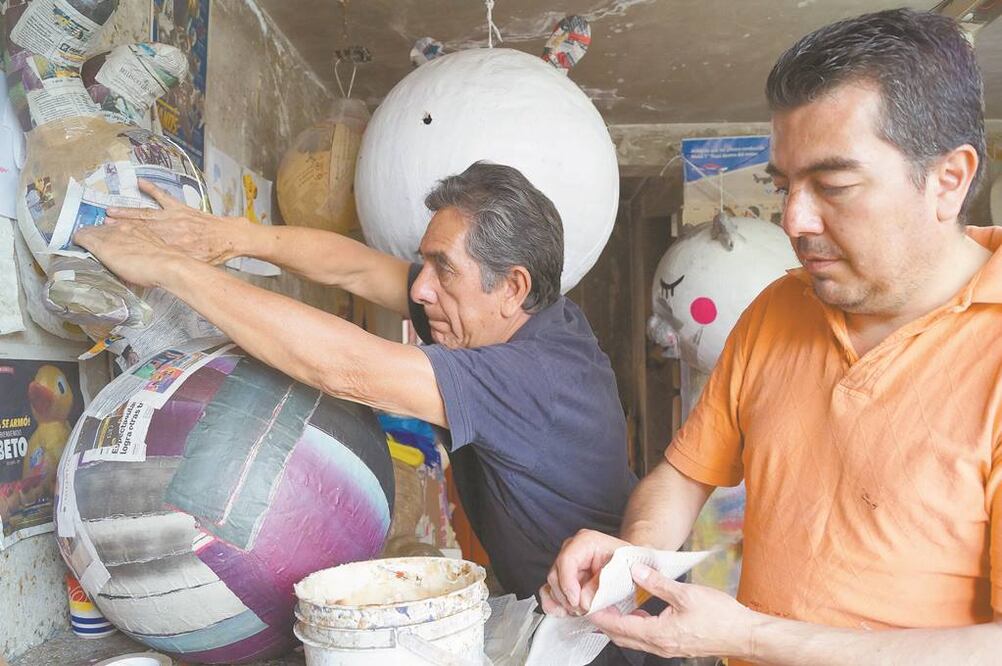 Tras perder su local, Hugo Mena (der.) instaló su taller de piñatas en su casa, donde el espacio dista mucho de ser el adecuado. Foto/PATRICIA RAMÍREZ. EL UNIVERSAL