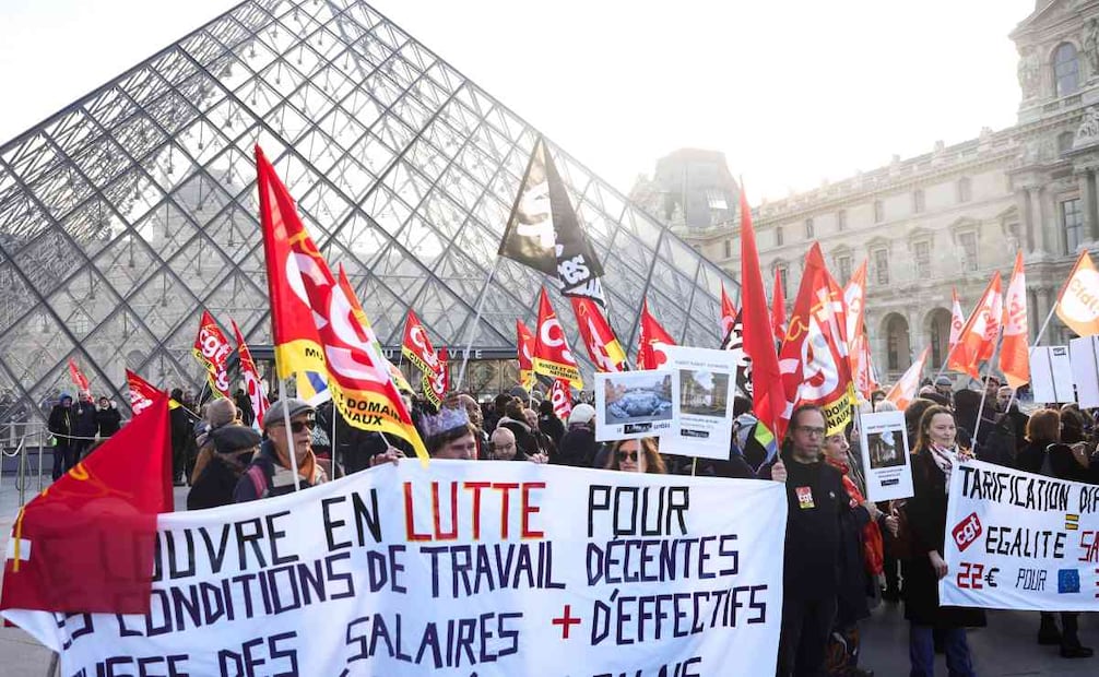 Trabajadores del Louvre pertenecientes a diversos sindicatos, entre ellos CGT, CFDT y SUD, sostienen una pancarta con el mensaje El Louvre lucha por unas condiciones laborales dignas, salarios más altos y más personal. Contra el deterioro del palacio y el proyecto LNR durante una manifestación frente a la pirámide del museo en el primer día de huelga en París, Francia, el 15 de diciembre de 2025. Unos 400 trabajadores del Louvre han iniciado hoy una huelga para exigir mejores condiciones laborales y mejoras en las instalaciones del museo. Foto: EFE