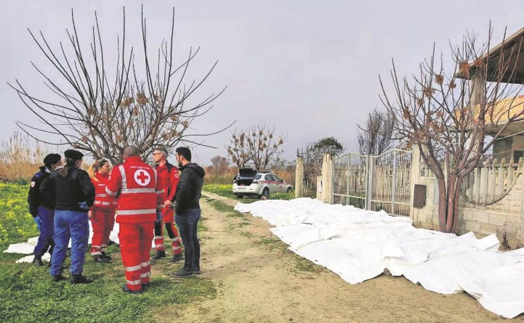 Carabineros y personal de la Cruz Roja conversan al lado de los cuerpos recuperados de migrantes tras el naufragio de su embarcación, en la provincia italiana de Crotone. Foto: EFE