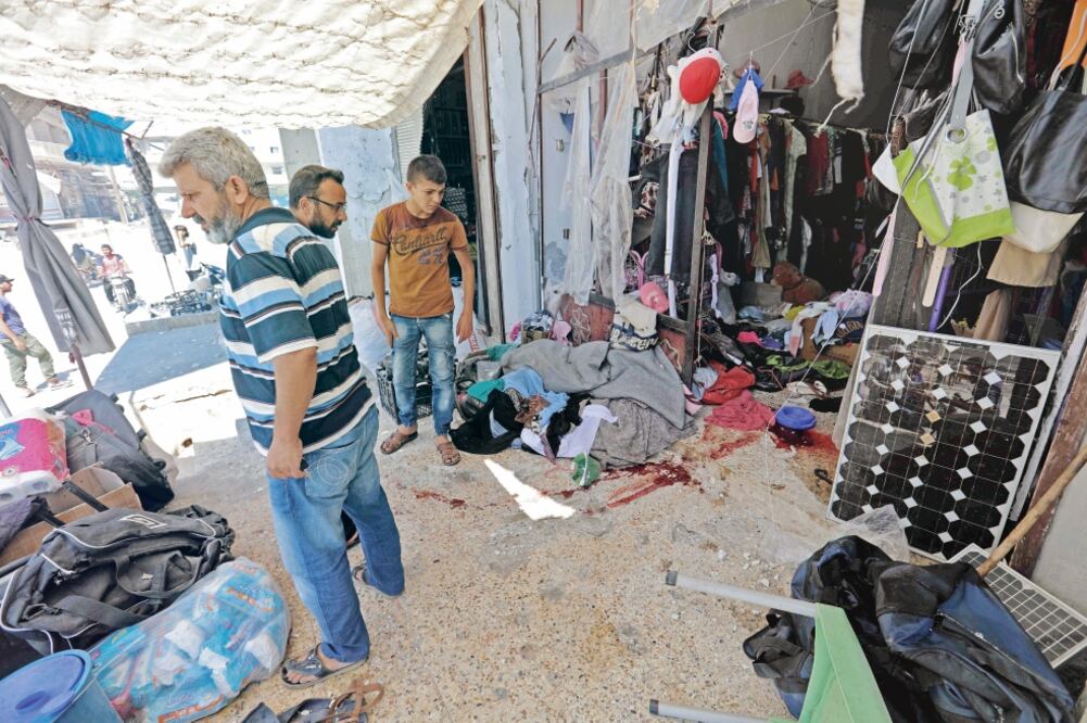 Ciudadanos sirios observan los daños causados en una tienda tras un bombardeo aéreo registrado ayer que se atribuyó a las fuerzas rusas. (OMAR HAJ KADOUR. AFP)