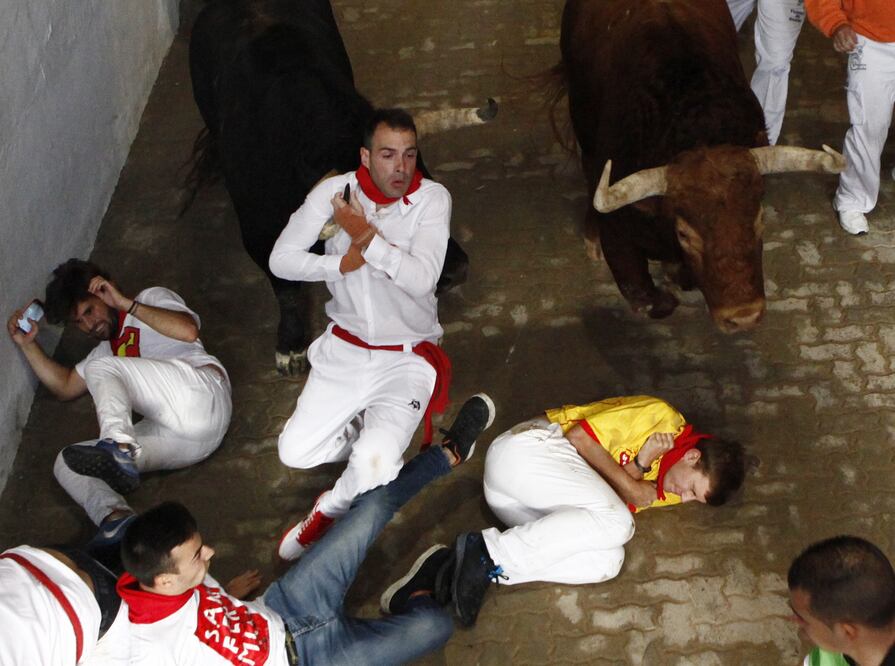Varios mozos pasan apuros ante los toros de la ganadería de Yeltes, en el tramo del Callejón, durante el cuarto encierro que ha sido rápido (EFE/Peio Hernández)