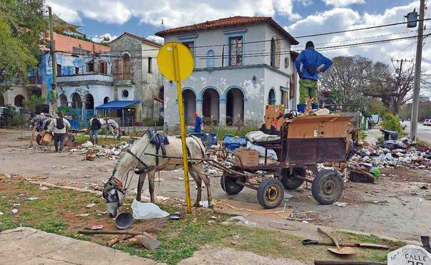 Cubanos recogen basura acumulada en una calle de La Habana. La falta de gasolina impide que pase el camión recolector. Foto: EFE
