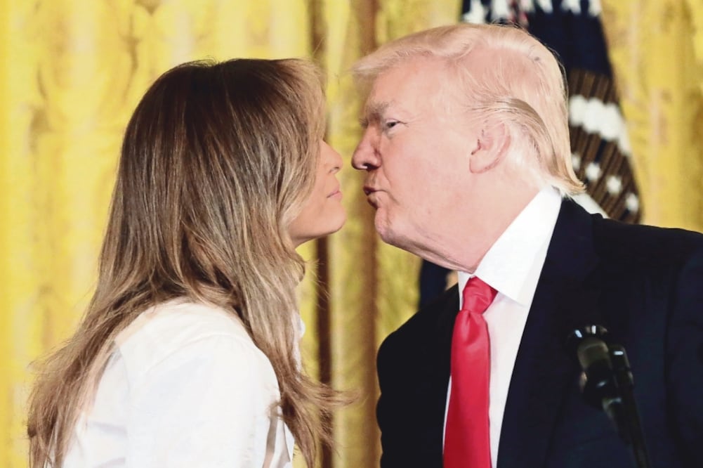 El presidente de Estados Unidos, Donald Trump, besó ayer a la primera dama, Melania Trump, durante la celebración de madres militares en la Casa Blanca, en Washington. (YURI GRIPAS. REUTERS)