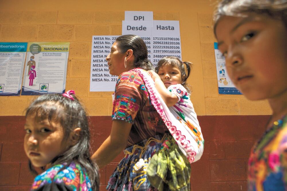 Una mujer acompañada por sus hijos ingresó ayer a un colegio electoral durante los comicios generales en Chinautla, en las afueras de la Ciudad de Guatemala. Foto: OLIVER DE ROS. AP