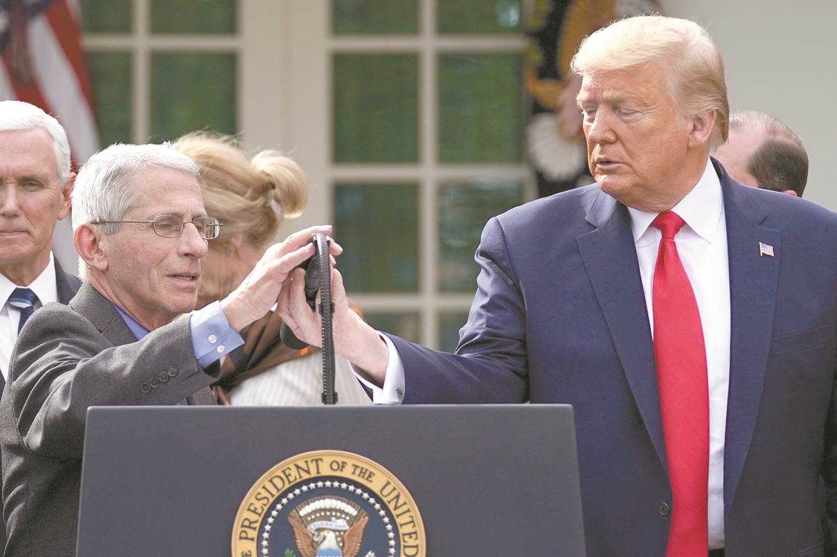 El presidente de EU, Donald Trump, ajusta el micrófono para el doctor Anthony Fauci en una conferencia sobre el coronavirus en la Casa Blanca. Foto: EVAN VUCCI. AP
