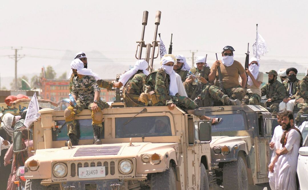 Talibanes montan guardia, mientras la gente celebra la retirada de las fuerzas estadounidenses, en Kandahar. Foto: JAVED TANVEER. AFP