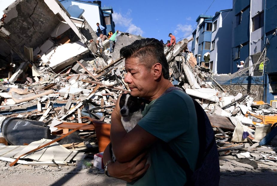 Un hombre con su perrito camina junto a los escombros de un edificio colapsado en la ciudad colombiana de Pereira, tras un terremoto de magnitud 7.4. FOTO: JAIME SALDARRIAGA. AFP