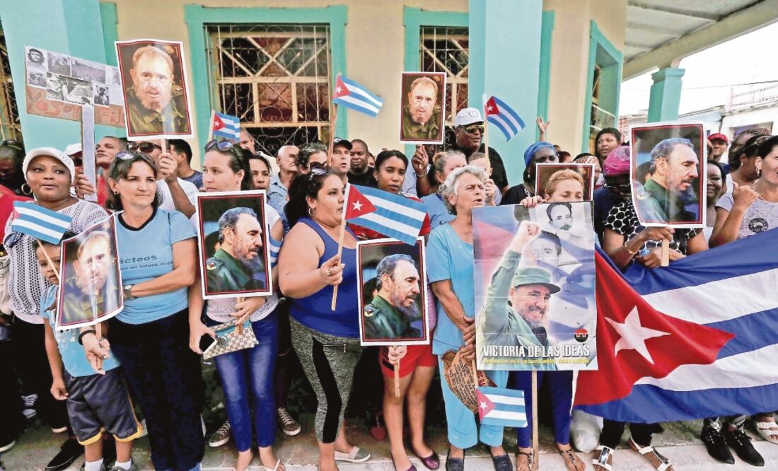 Cubanos portan banderas y retratos de Fidel Castro mientras esperan el paso de la caravana con las cenizas en Ciego de Ávila, Cuba (ENRIQUE DE LA OSA. REUTERS)