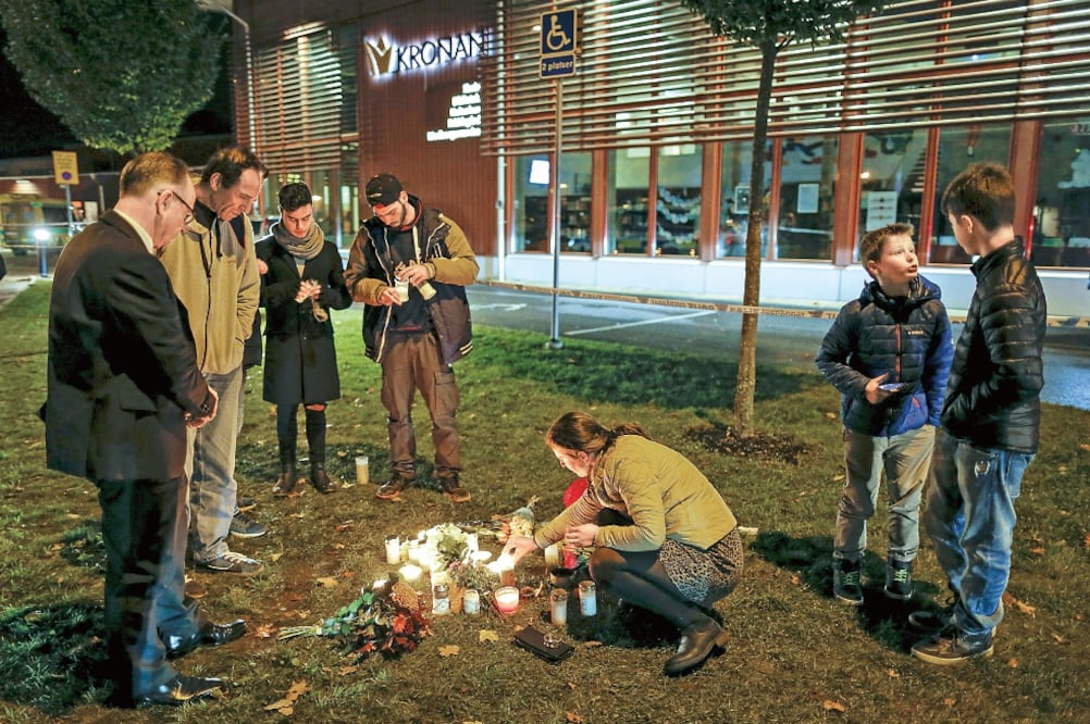 gente coloca velas y flores en la escuela Kronan de Trollhätan, donde un sujeto enmascarado atacó con una espada o un cuchillo largo (ADAM IHSE. REUTERS)