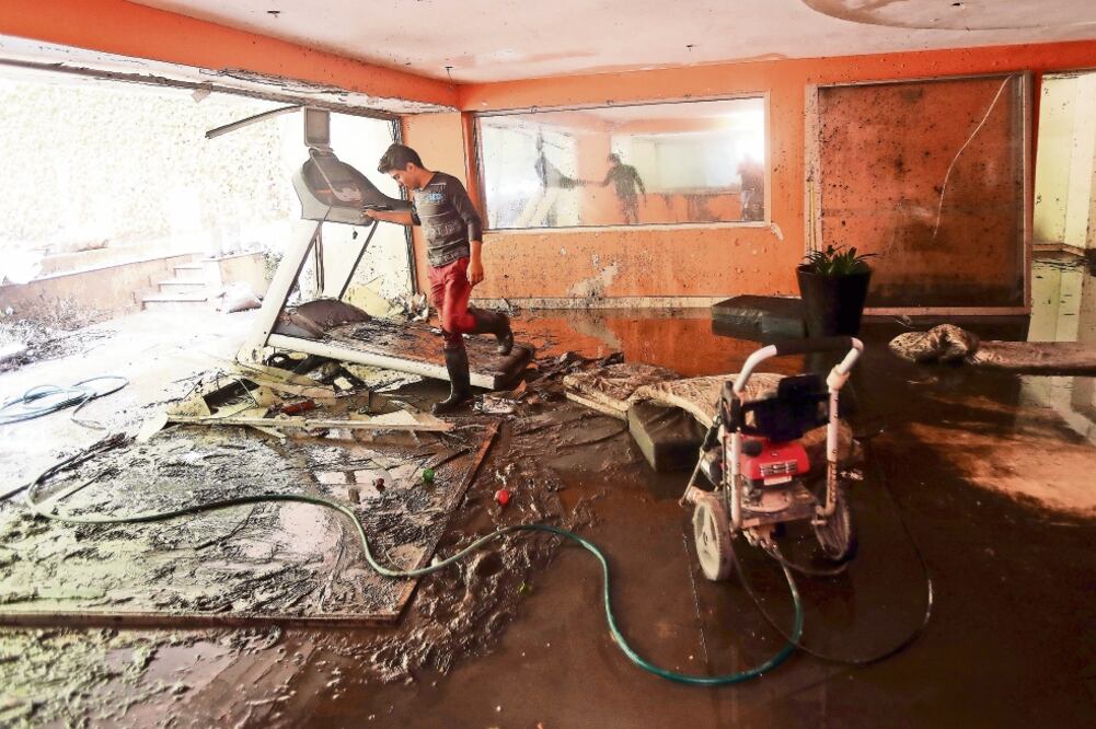 Habitantes de la calle Bosque de Canelos, en la colonia Bosques de las Lomas, limpiaban ayer sus viviendas que por segunda ocasión se inundaron en tres semanas; algunos decidieron dejar sus hogares (JUAN CARLOS REYES. EL UNIVERSAL)