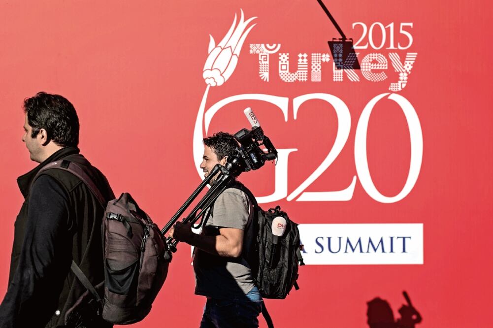 Un representante de los medios camina frente a un panel en el área principal de la sede de la Cumbre de Líderes del Grupo de los 20 (G-20), que se celebrará del 15 al 16 de noviembre, en la ciudad mediterránea (XINHUA)