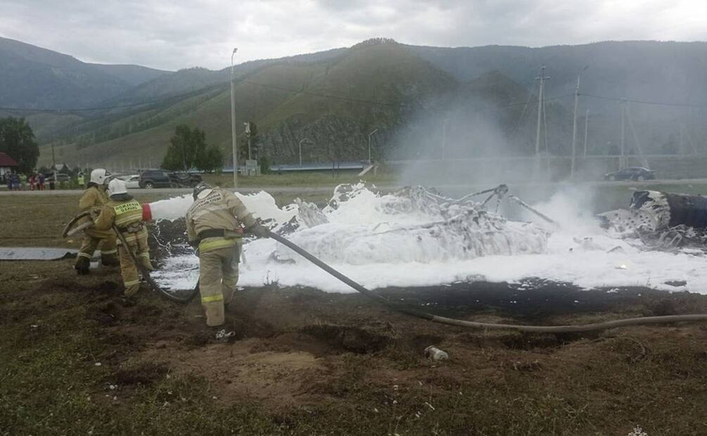 Bomberos apagan un helicóptero Mi-8 después del accidente cerca de la aldea de Tyungur, República de Altai, en el sur de Siberia. Foto: AP