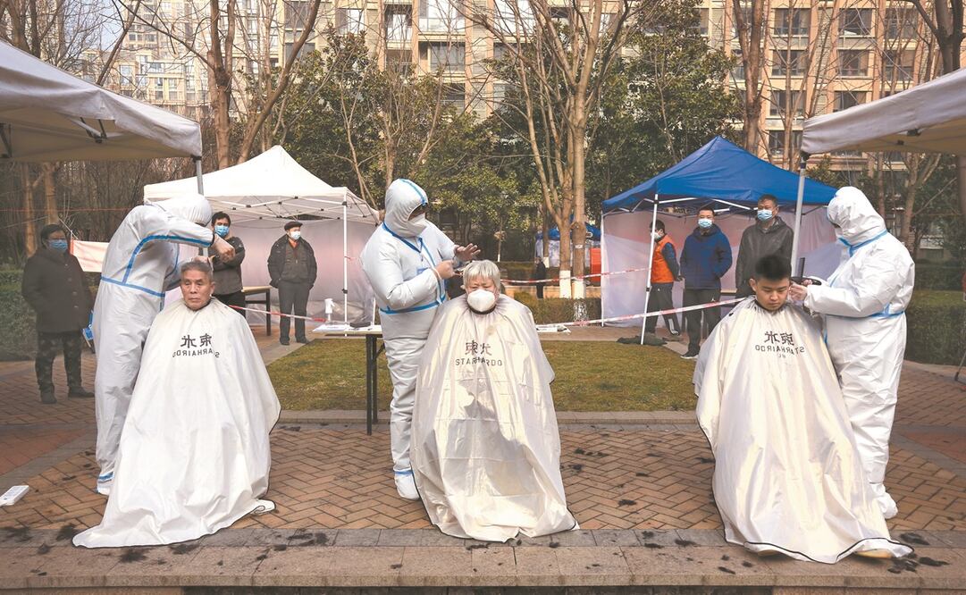 Peluqueros con trajes sanitarios y residentes en un bloque que quedó bajo confinamiento en Xi’an, localidad china. Foto: AP
