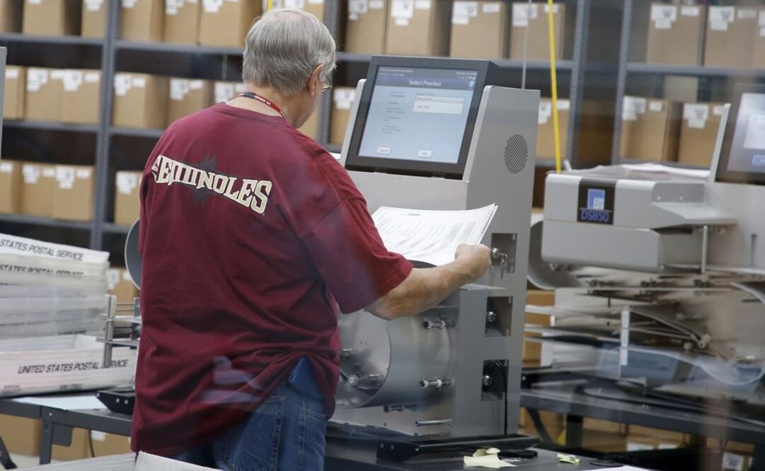 Un trabajador electoral introduce boletas en una máquina de tabulación en la oficina del Supervisor de Elecciones del Condado de Broward (Foto: AFP)