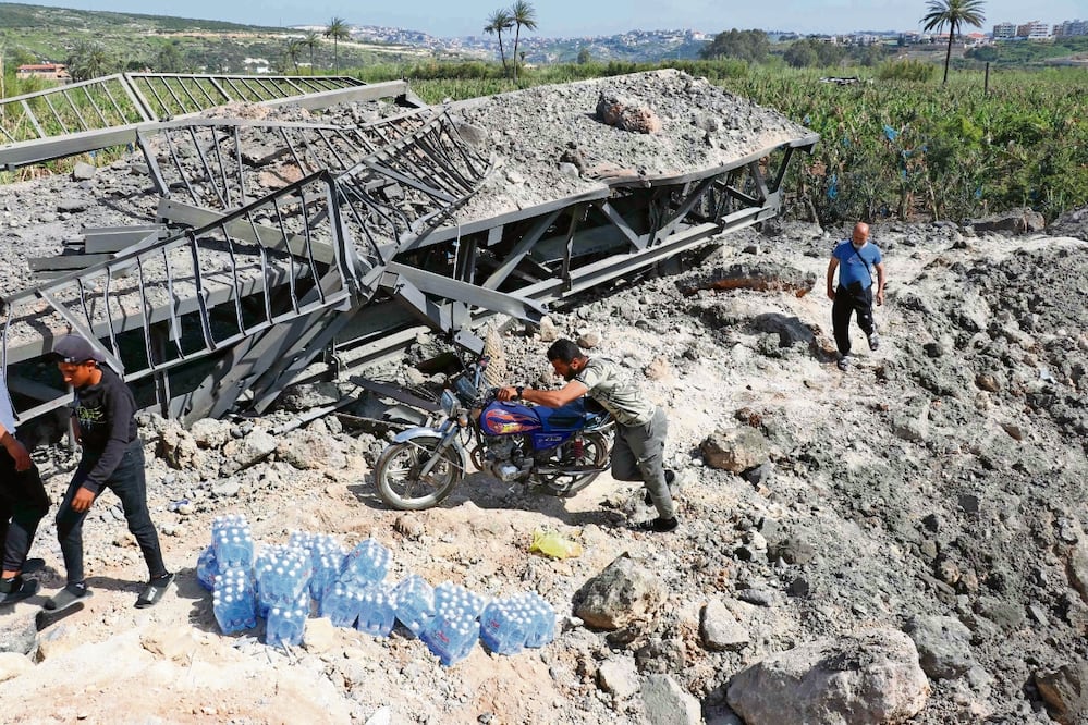 Libaneses cruzan a pie el puente Qasmieh, que conecta las ciudades de Tiro y Sidón, tras ser atacado por la aviación israelí. Foto: Kawnat Haju / AFP