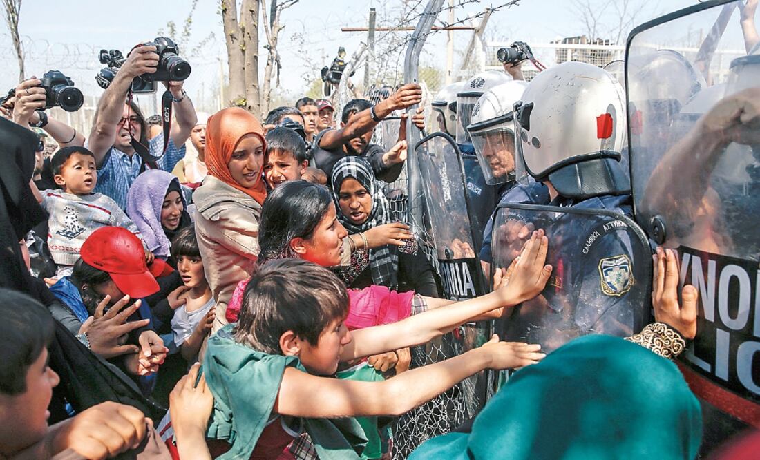 Policías intentaban ayer frenar a migrantes y refugiados que buscaban abrir una cerca en la frontera entre Grecia y Macedonia, en un campamento cerca de la localidad de Idomeni (MARKO DJURICA. REUTERS)