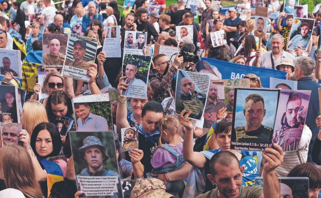 Personas, con fotos de sus familiares desaparecidos mientras soldados ucranianos regresan del cautiverio en un intercambio de prisioneros de guerra entre Rusia y Ucrania, en Chernyhiv. Foto: Evgeniy Maloletka/ AP