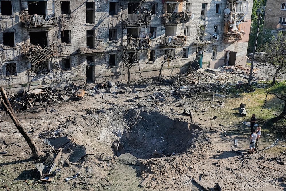 Ucranianos pasan junto a un edificio impactado por los ataques rusos, en Kiev. FOTO: EFREM LUKATSKY. AP