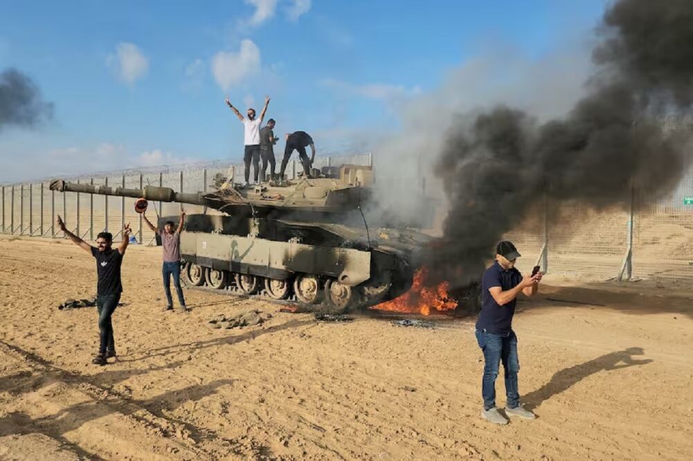 Los palestinos celebran junto a un tanque israelí destruido en la valla de la Franja de Gaza al este de Khan Yunis el sábado 7 de octubre de 2023. FOTO: HASSAN ESLAIAH. AP