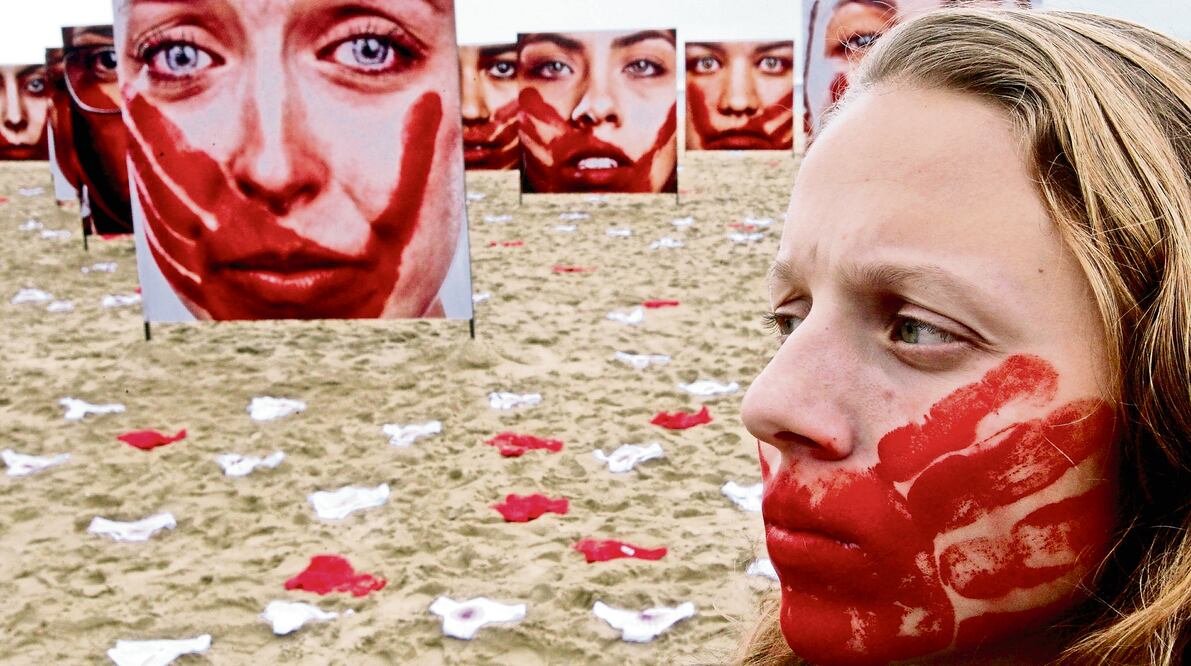 Imagen ilustrativa. Una mujer camina frente a imágenes de mujeres desplegadas durante una protesta contra los abusos hacia las mujeres en Brasil (Foto: Xinhua)