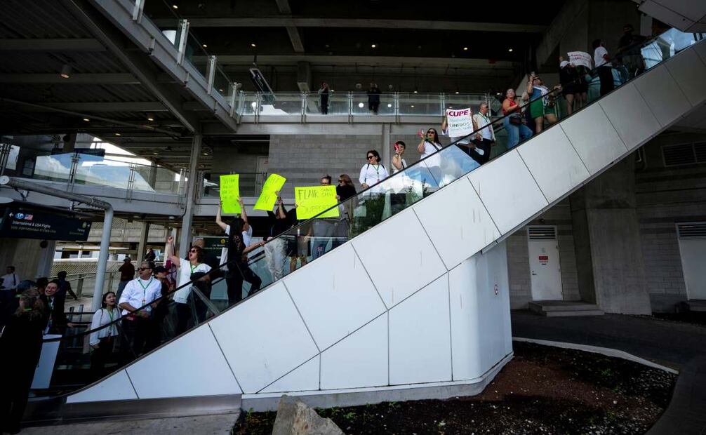 Picketers ride an escalator to march around the Vancouver International Airport in Richmond, British Columbia, Sunday, Aug. 17, 2025. (Ethan Cairns/The Canadian Press via AP)
