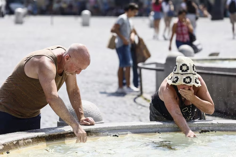 Un grupo de personas se refresca en una fuente en un día caluroso en la Plaza de España de Roma, bajo la Escalinata Española. FOTO: AP
