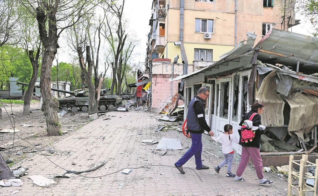 Una familia atraviesa por una destruida calle de Mariupol, bajo control de la prorrusa República Popular de Donetsk, en Ucrania. Foto: Alexei Alexandrov. AP