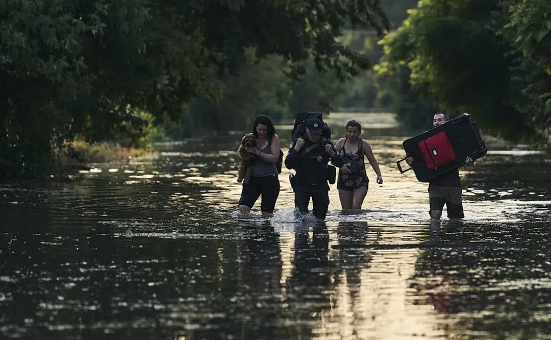 Residentes cargan sus pertenencias mientras evacuan un vecindario inundado en Jersón, Ucrania, el martes 6 de junio de 2023. Foto: AP