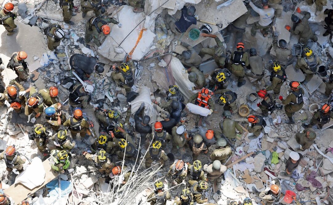 Israelíes buscan entre los escombros a personas desaparecidas tras el derrumbe de un edificio impactado por un misil iraní, en Bat Yam. Foto: EFE