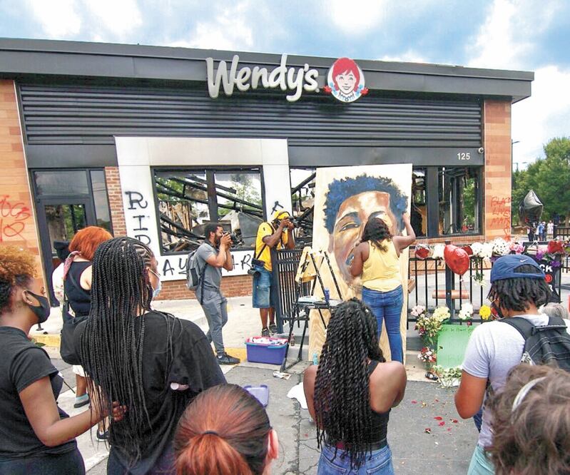 Ashley Dopson pinta una imagen de Rayshard Brooks en el estacionamiento de Wendy's en Atlanta, donde el hombre afroamericano fue asesinado a tiros por la policía de ese estado, el viernes por la noche. Foto: Teve Schaefer. AP