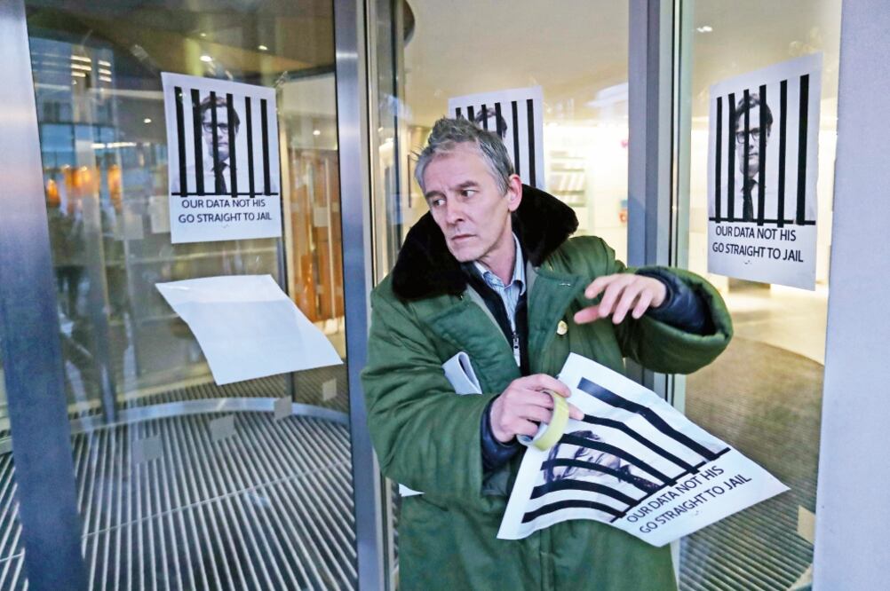 Un manifestante pega carteles en Londres contra el presidente ejecutivo de Cambridge Analytica, pidiendo que vaya a prisión. Foto: DANIEL LEAL-OLIVAS. AFP