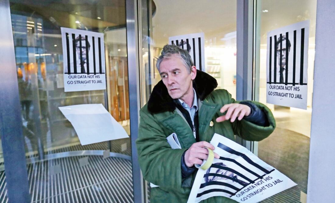 Un manifestante pega carteles en Londres contra el presidente ejecutivo de Cambridge Analytica, pidiendo que vaya a prisión. Foto: DANIEL LEAL-OLIVAS. AFP