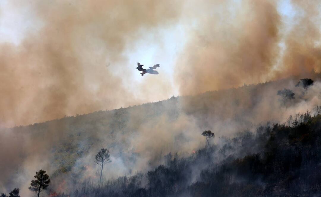 Un avión de extinción de incendios deja caer agua durante un incendio forestal en Grammatiko, noreste de Ática, Grecia. Foto: EFE