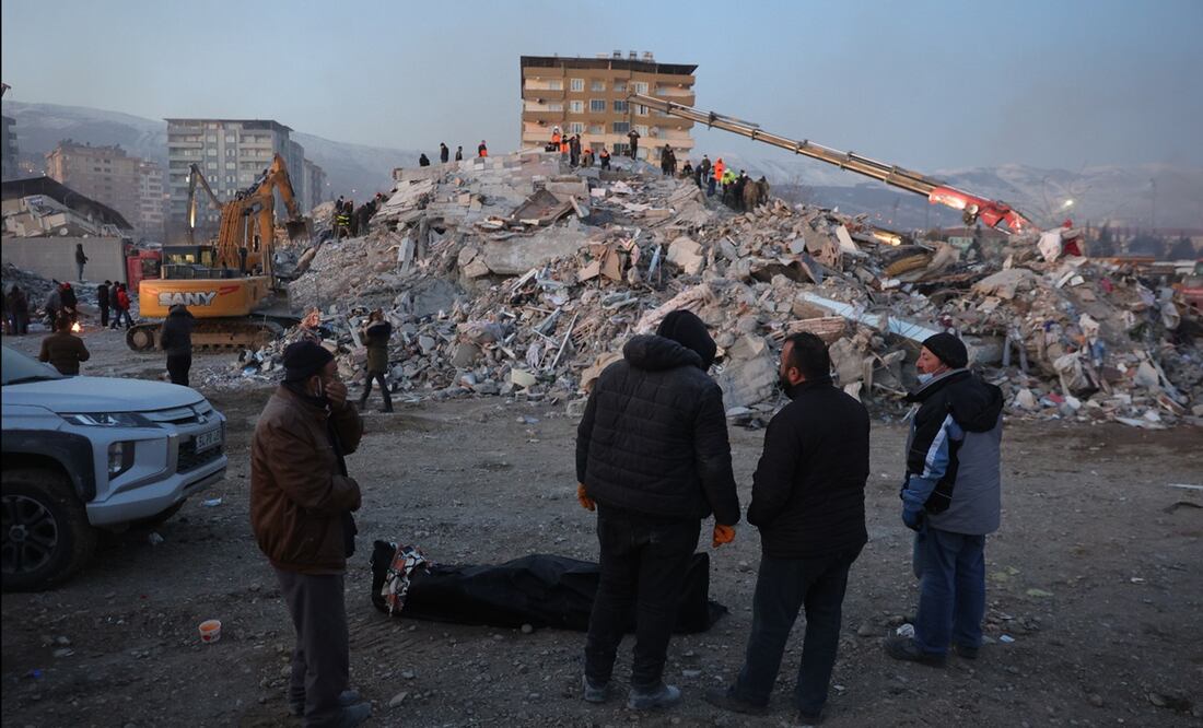 La gente se para alrededor de un cuerpo envuelto en una manta junto a los escombros de un edificio derrumbado en Kahramanmaras, sureste de Turquía. FOTO: EFE