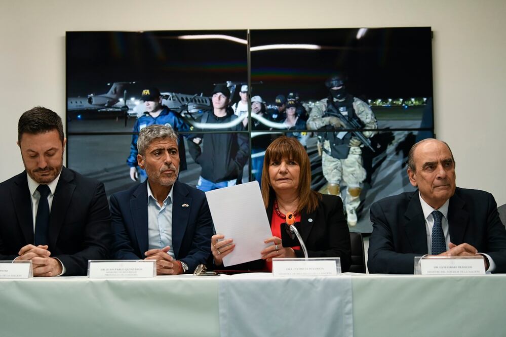 La ministra de Seguridad, Patricia Bullrich, segunda desde la derecha, el ministro de Defensa, Luis Petri, a la izquierda, el ministro de Seguridad de Córdoba, Juan Pablo Quinteros, segundo desde la izquierda, y el ministro del Interior, Guillermo Francos, a la derecha, dan una conferencia de prensa sobre la expulsión de la familia del prófugo narco ecuatoriano José Adolfo "Fito" Macías Villamar, mostrado en video detrás de ellos, en Buenos Aires. Foto: AP