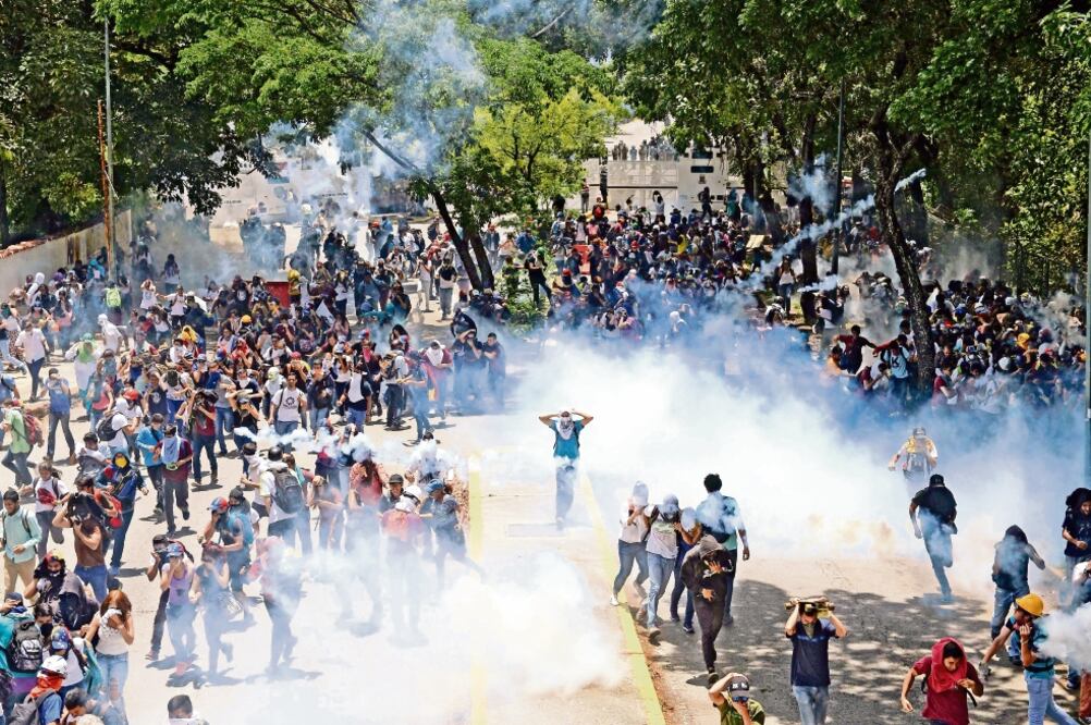 Estudiantes de la Universidad Central de Venezuela, durante los enfrentamientos de ayer contra la policía antimotines, en Caracas. La cifra de decesos en poco más de un mes de protestas es de 36. (FEDERICO PARRA. AFP)