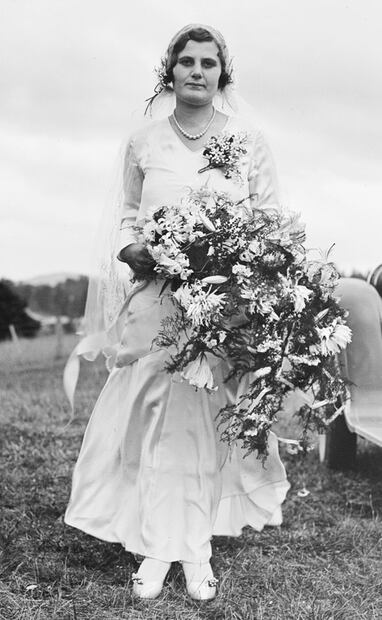 Fotografía de los años 20, de una novia y su enorme arreglo floral. Entre los tipos de ramos está el estilo oversize, grande y desordenado como el que se ve en la imagen. También existió el Biedermeier, popular a finales del siglo XVIII, con una formación circular de flores en sentido concéntrico, aunque los preferidos son los bouquet y de cascada. Foto: Wikimedia Commons.