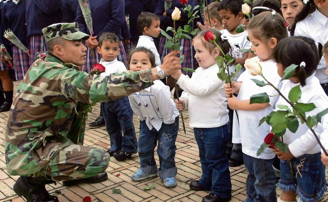 Un soldado reparte flores a menores durante una ceremonia en Bogotá. HRW alerta en un nuevo reporte sobre el reclutamiento de niños por parte de grupos armados. Foto: Mauricio Dueñas / AFP
