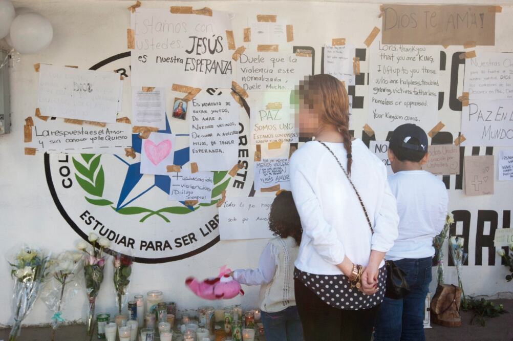 Personas observan los mensajes colocados en el Colegio Americano del Noreste, en la ciudad de Monterrey, donde ayer un joven de 15 años abrió fuego contra cuatro personas para luego suicidarse. (EFE)